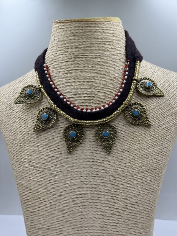 an artisan-crafted necklace from Nepal, showcasing a raw-cut blue turquoise stone set in a polished brass pendant with silver filigree